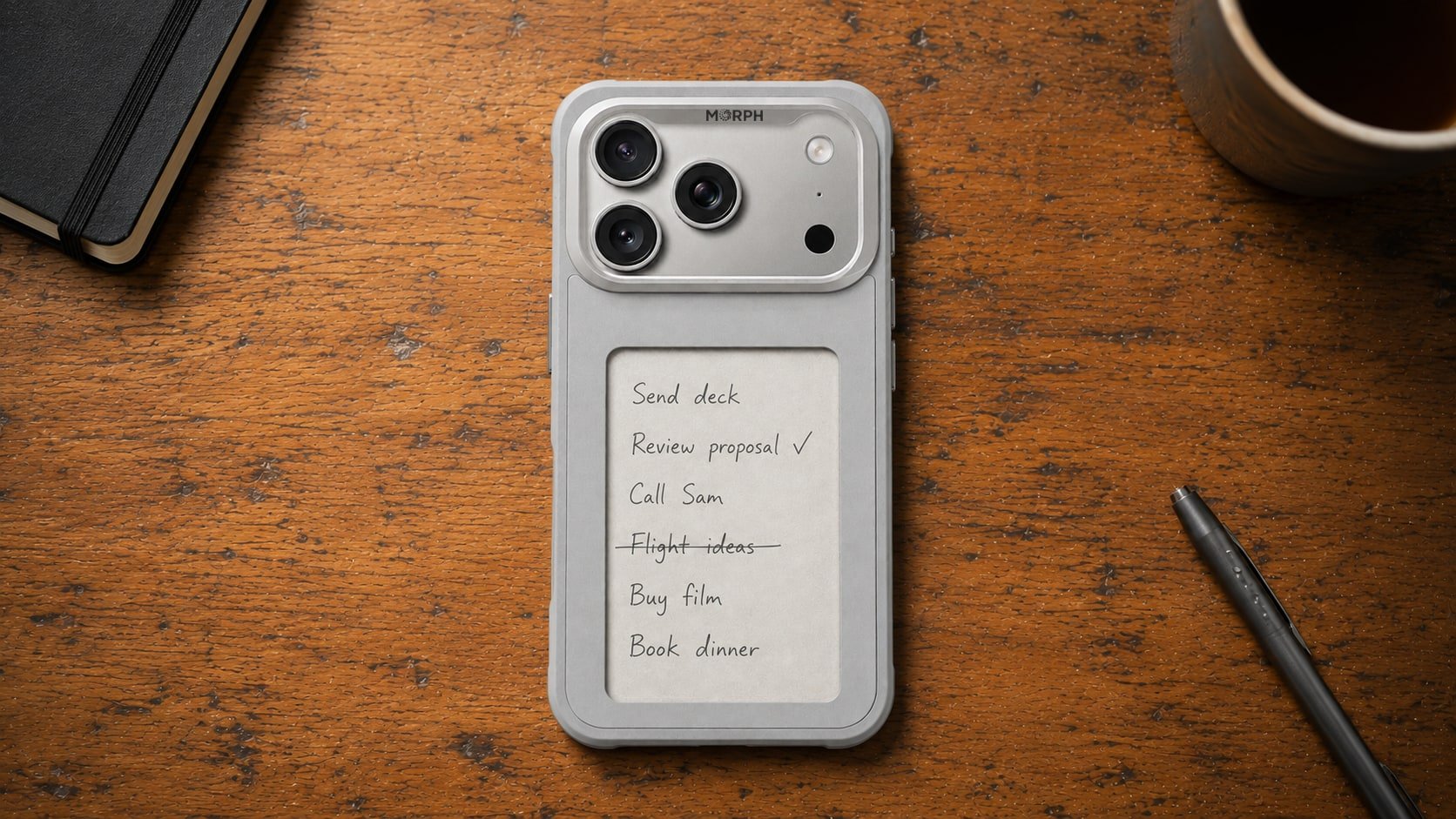 A silver case flat on a timber desk beside a notebook, a pen and a coffee, its panel holding a handwritten list of the day tasks.